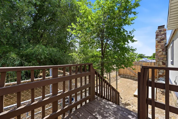Spacious wood-finish deck with a matching railing, descending to a backyard with a natural wood fence