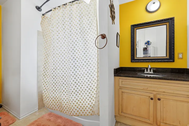 Bathroom featuring a light wood-finish vanity with a dark countertop and an ornate framed mirror