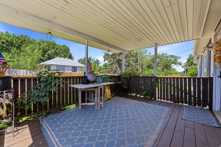 Spacious covered deck featuring wood plank flooring and a dark wood slatted railing