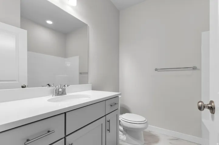 Vanity with an integrated sink, polished chrome faucet, gray cabinetry, and a large wall mirror