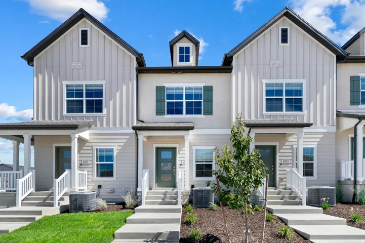 Exterior featuring board and batten siding, multiple windows, a covered entry, and a manicured lawn