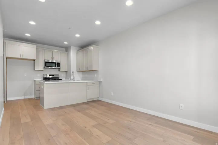 Kitchen featuring a central island, stainless steel appliances, light-toned cabinetry, and recessed lighting