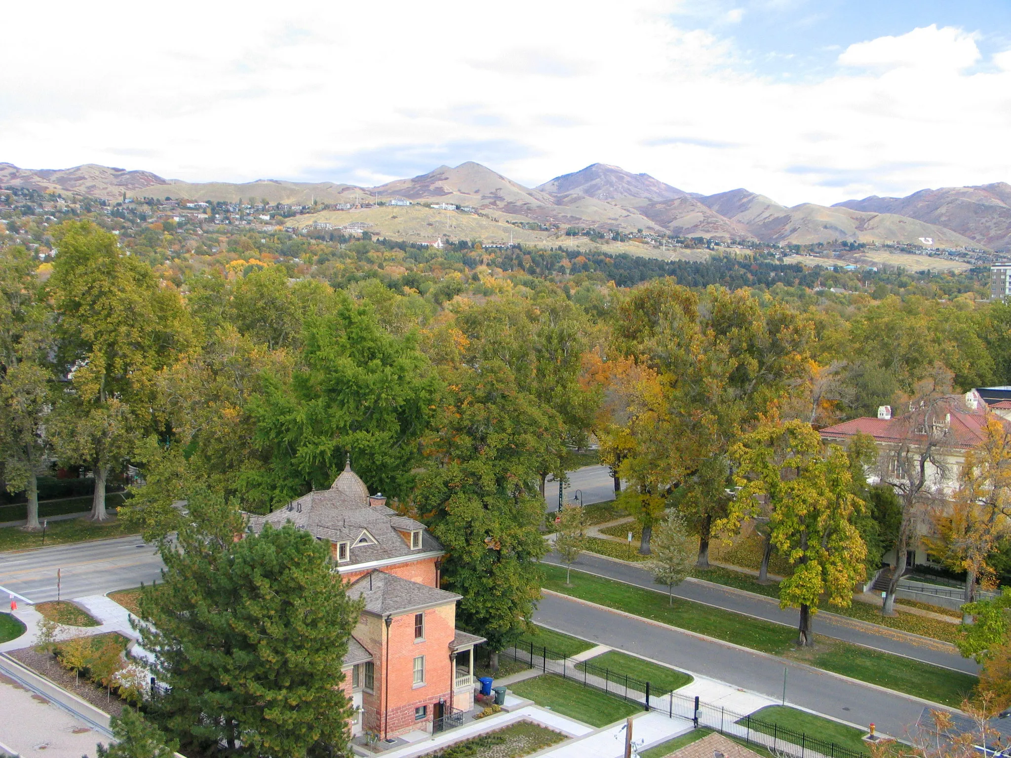 Historic brick residence with an intricate roofline, surrounded by mature trees, and featuring a prominent mountain backdrop