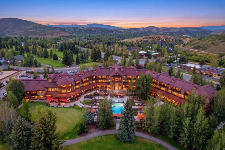 Expansive property featuring a large multi-story structure with a red tile roof, multiple outdoor patios, an outdoor swimming pool, and a putting green