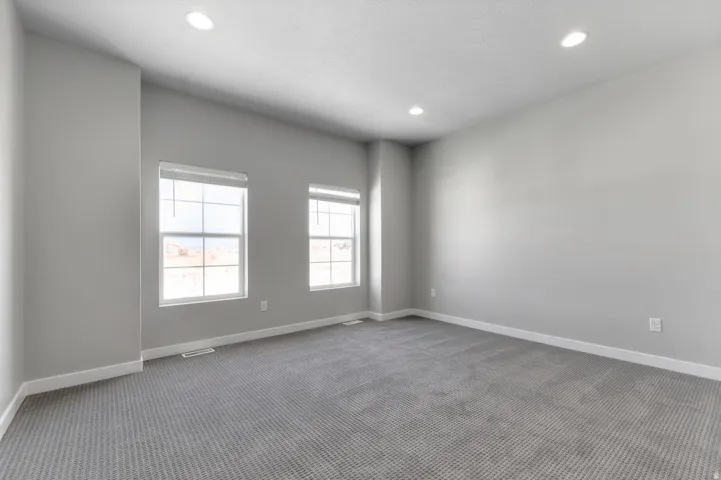 Spacious room with recessed lighting, two windows, and gray patterned carpeting