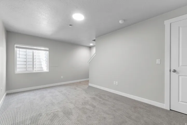 Carpeted flooring, neutral wall tones, recessed lighting, and a white paneled door