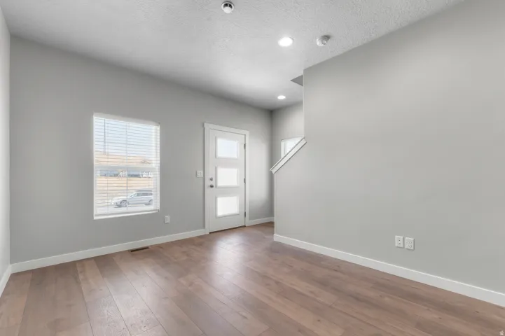 Wood-finish flooring, recessed lighting, and a modern entry door with frosted glass panels
