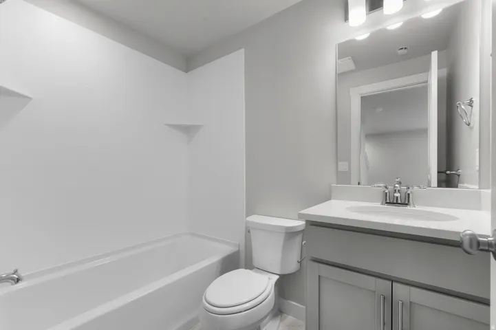Full bathroom featuring a single vanity with a solid surface countertop, undermount sink, and chrome fixtures