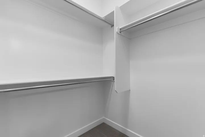 Walk-in closet with multiple hanging rods, integrated shelving, and carpet flooring