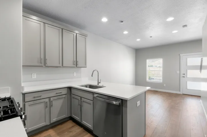 Kitchen featuring gray shaker-style cabinetry, white countertops, stainless steel appliances, and wood-finish flooring