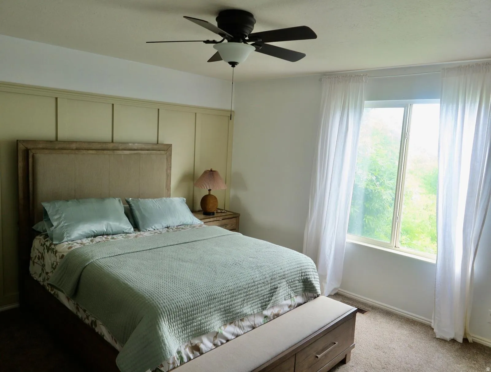 Wall paneling accentuates this room, featuring a large window with sheer drapery
