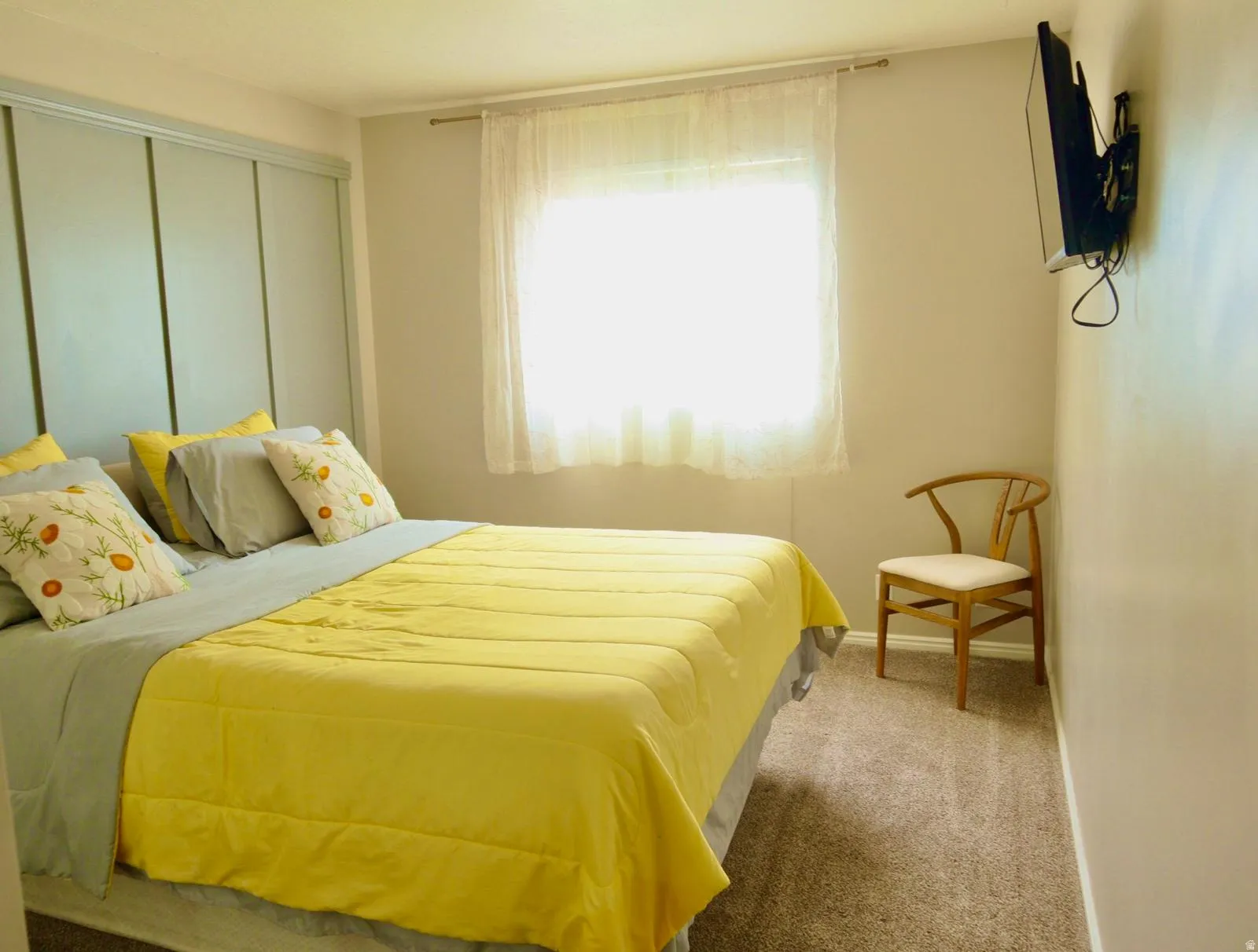 Bedroom featuring a built-in paneled headboard, carpeted flooring, and a wall-mounted television bracket
