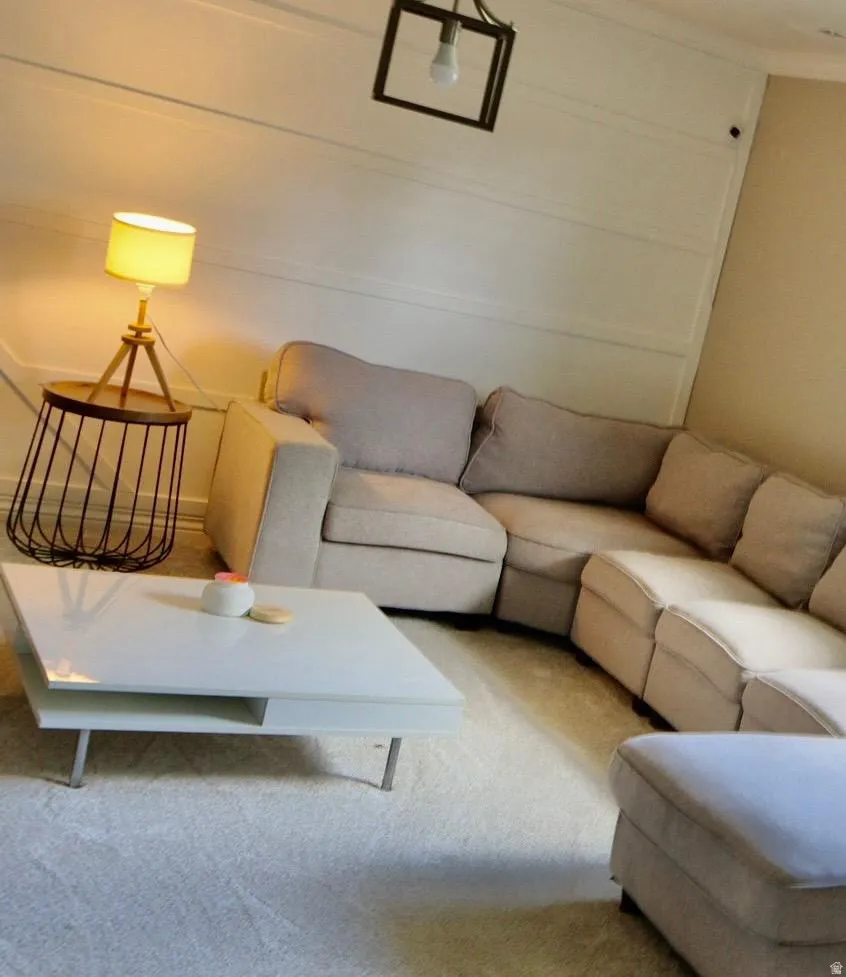 White paneled wall with a decorative light fixture, featuring plush carpet flooring and a corner seating arrangement