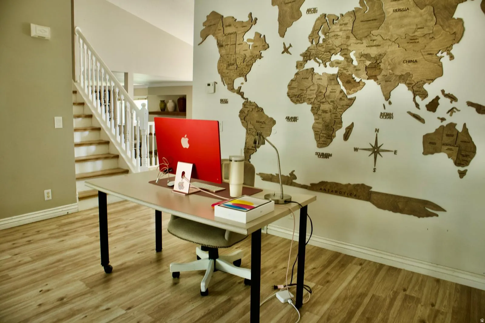Wood-finish flooring extending from the foreground into the background, a white staircase with wood treads and white risers, and light-toned walls