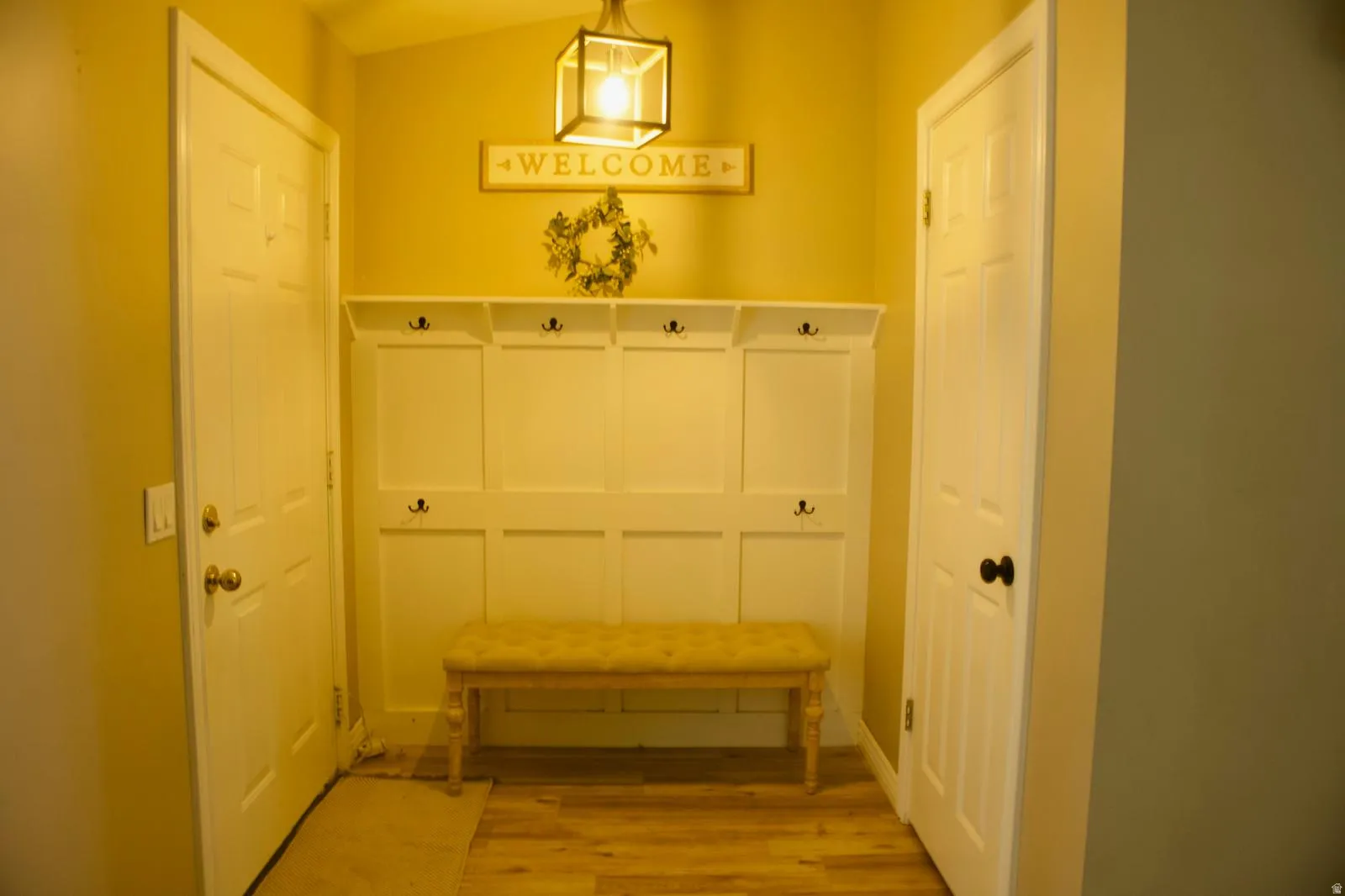 Entryway featuring a built-in white mudroom bench with coat hooks and overhead storage cubbies