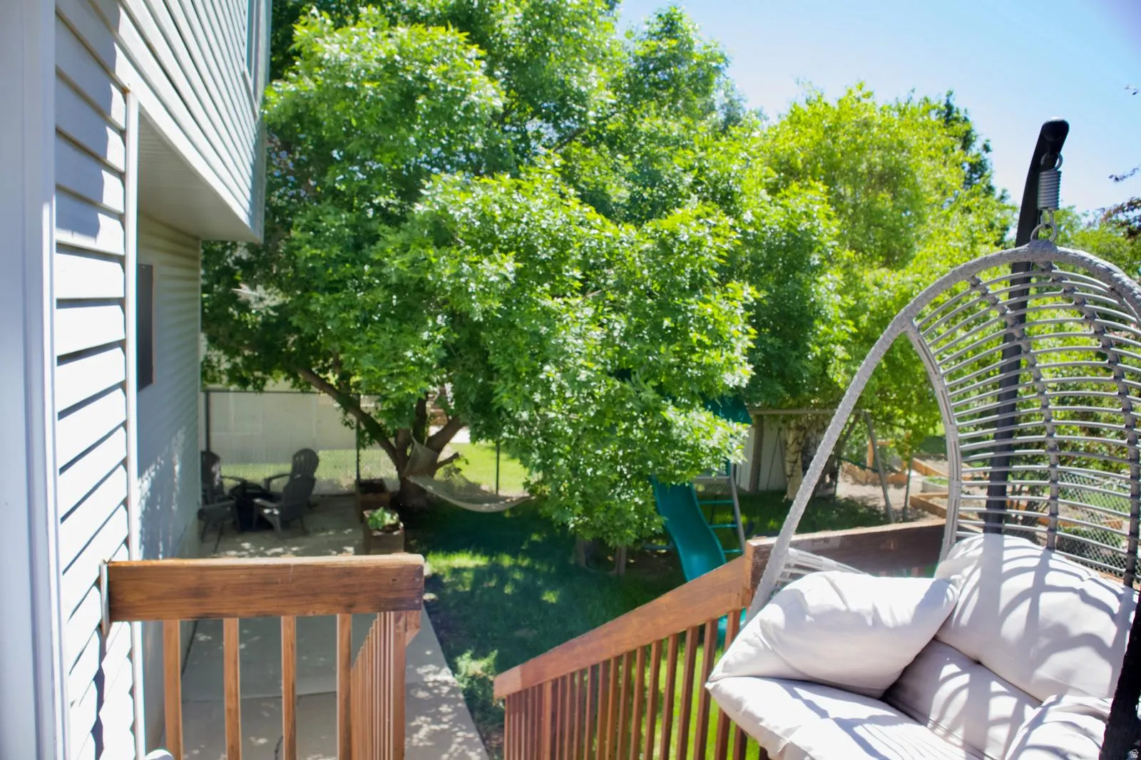 Expansive backyard featuring a manicured lawn, mature trees, and a ground-level patio