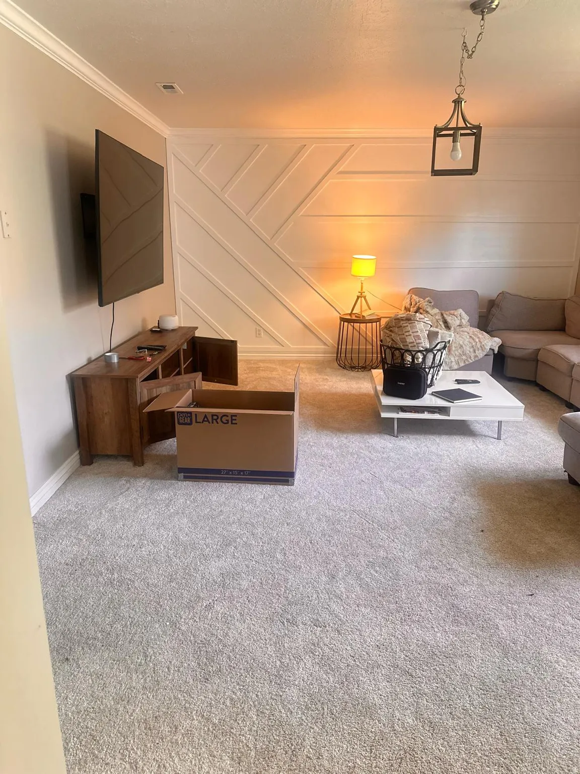 Living area featuring a detailed accent wall with geometric paneling, crown molding, and recessed lighting