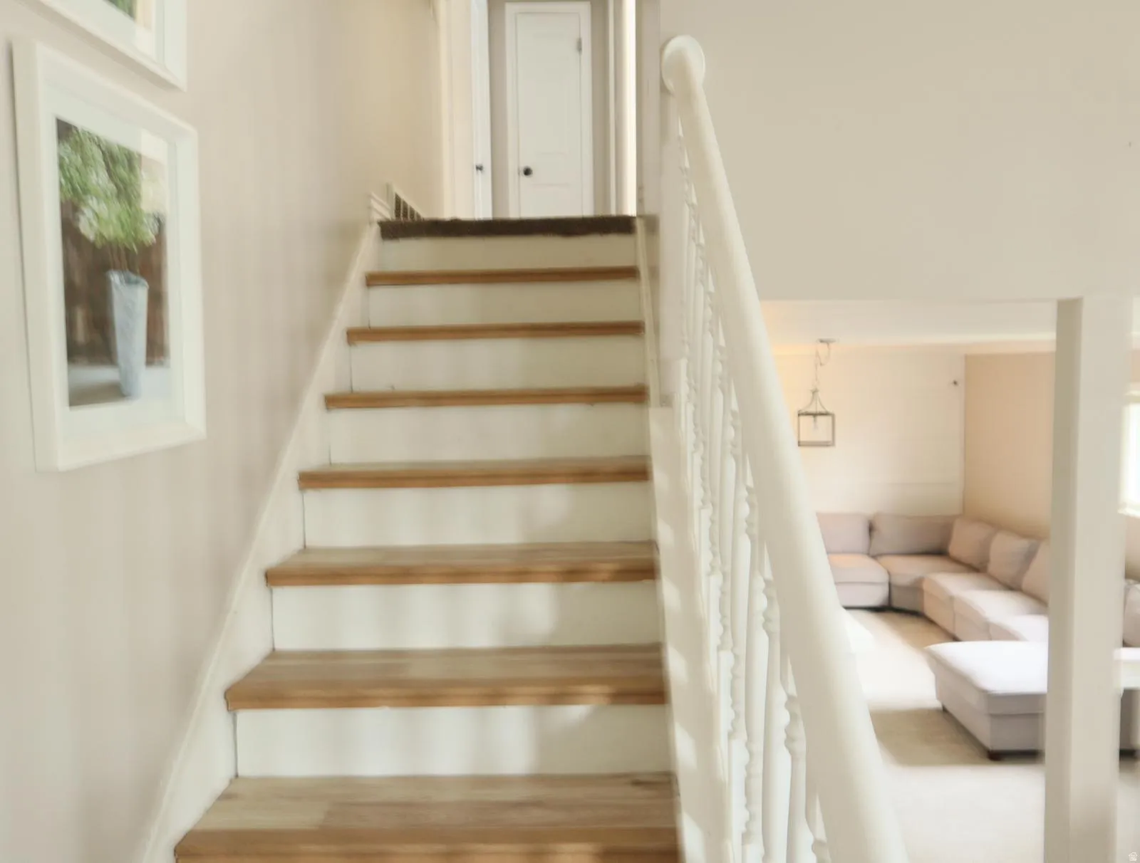 Staircase featuring wood-finish treads and white risers with a painted white balustrade