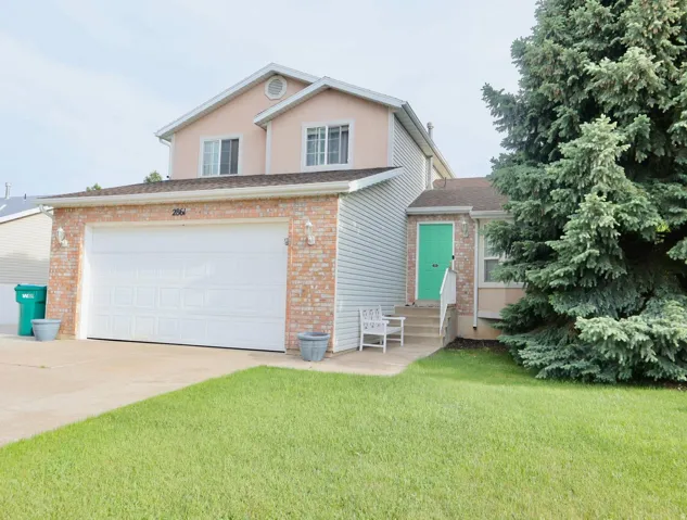 Two-story residence featuring a brick facade garage, an attached two-car garage, and a lush green lawn