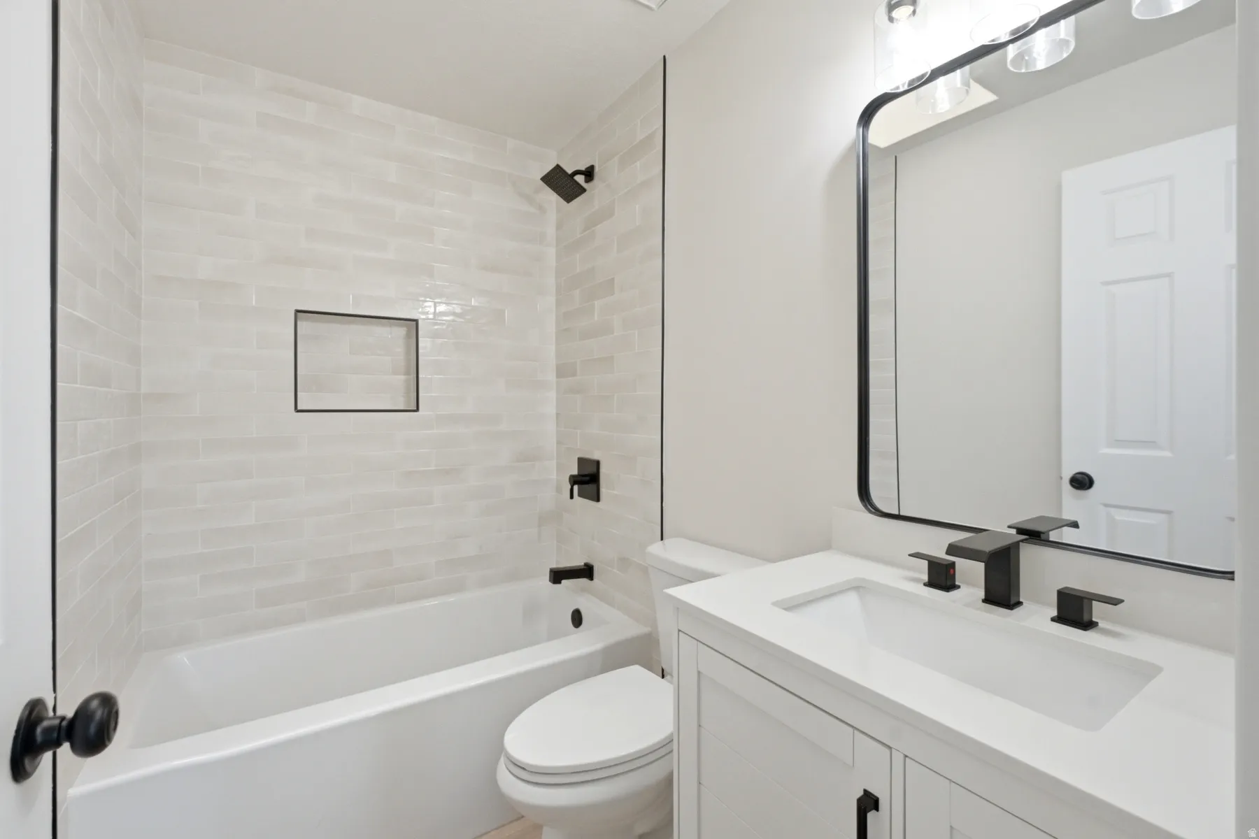 Bathroom featuring a white subway tile surround, matte black shower fixtures, and a recessed shower niche