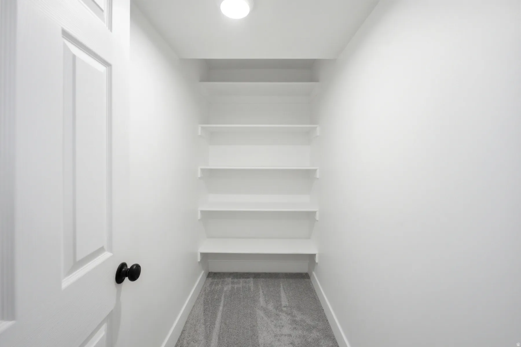 Built-in shelving unit providing five levels of storage, recessed lighting, and grey carpet flooring