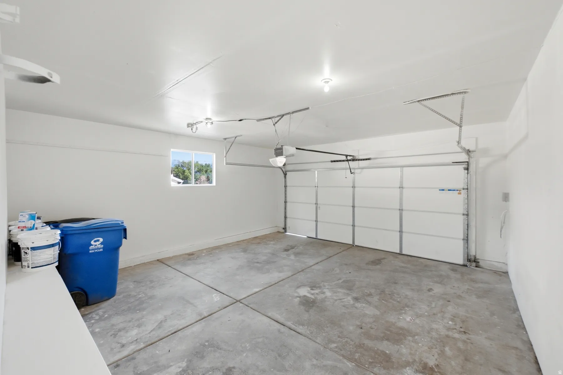 Spacious garage featuring a concrete floor, bright white walls, and a single garage door