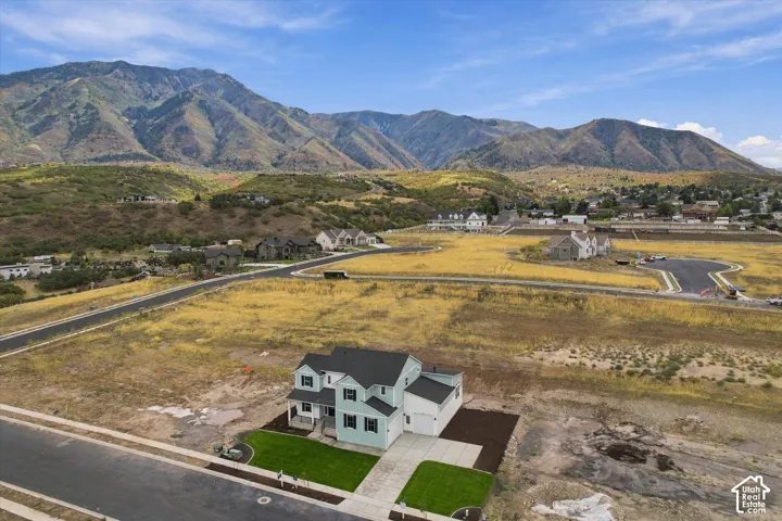 Two-story residence featuring a shingled roof, light-toned exterior siding, an attached garage, and mountain scenery