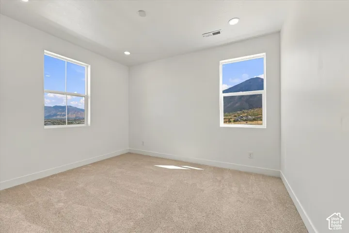 Neutral-toned wall interior featuring recessed lighting, plush wall-to-wall carpeting, and double-pane windows showcasing mountain scenery