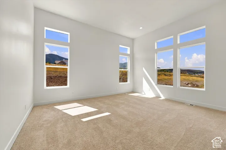 High-ceiling room featuring expansive windows, neutral wall finishes, carpeted flooring, and mountain scenery