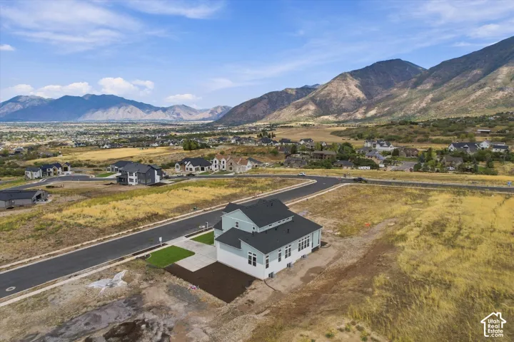 Multi-level residence featuring a dark pitched roof, two-tone siding, and a concrete driveway, set against a backdrop of mountain ranges