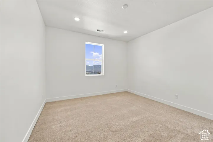 Neutral-toned wall-to-wall carpeting, recessed ceiling lighting, and a single-pane window with mountain scenery