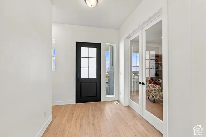 Entryway featuring wood-finish flooring, a six-pane glass entry door with matte black hardware, and double French doors with glass panels