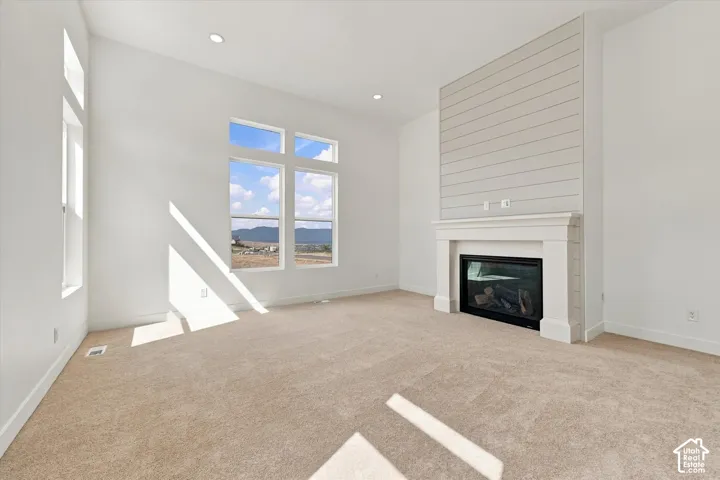 Living area featuring high ceilings, large windows with mountain scenery, recessed lighting, and a fireplace with shiplap detailing