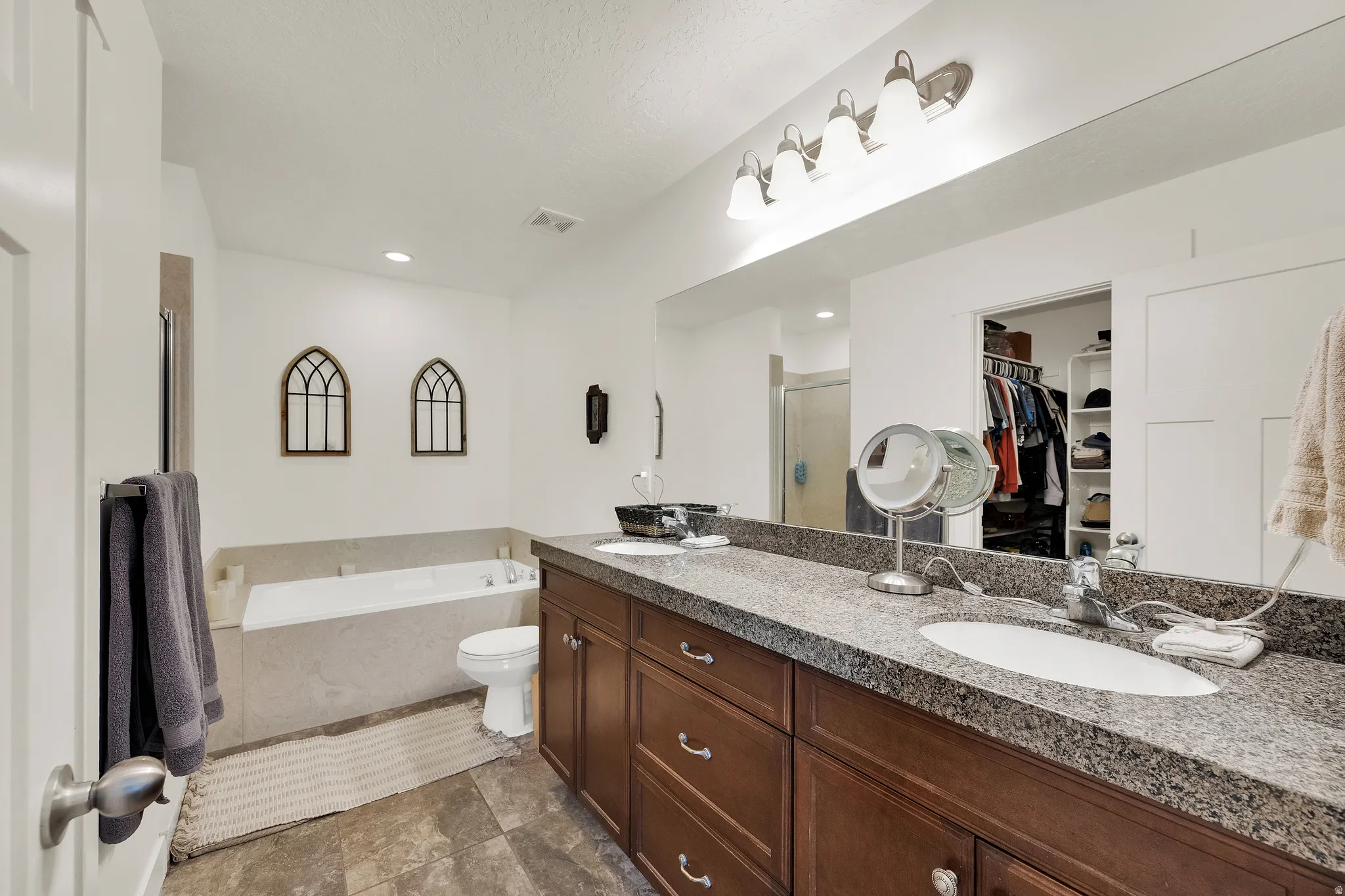 Dual vanity with granite-style countertop, wood-finish cabinetry, and undermount sinks