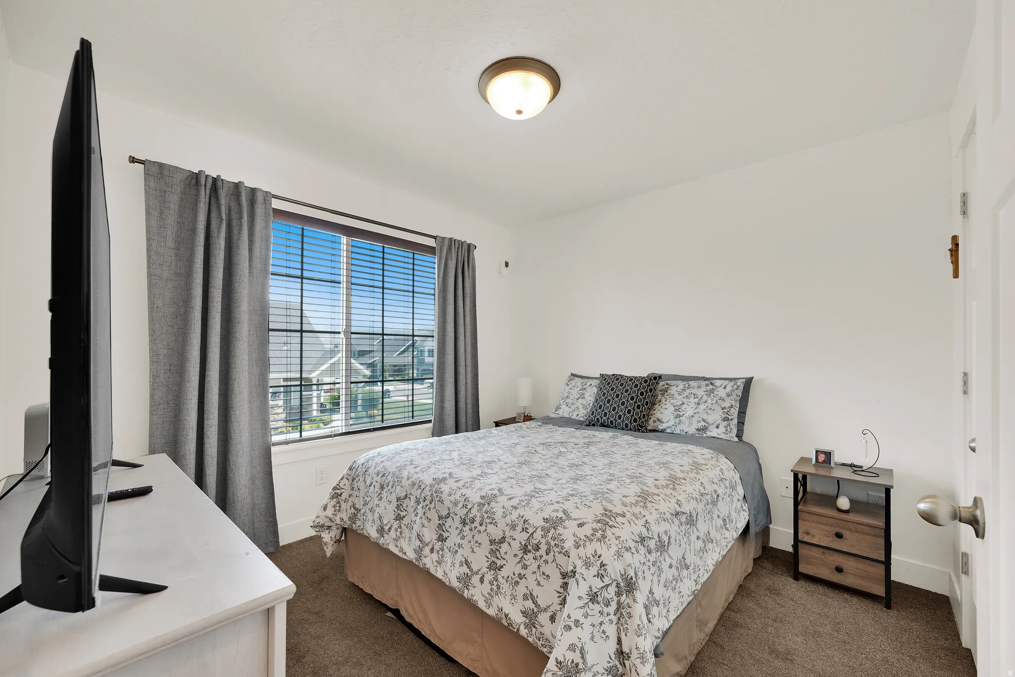 Carpeted room featuring a double window with blinds, white trim, and a semi-flush mount ceiling fixture