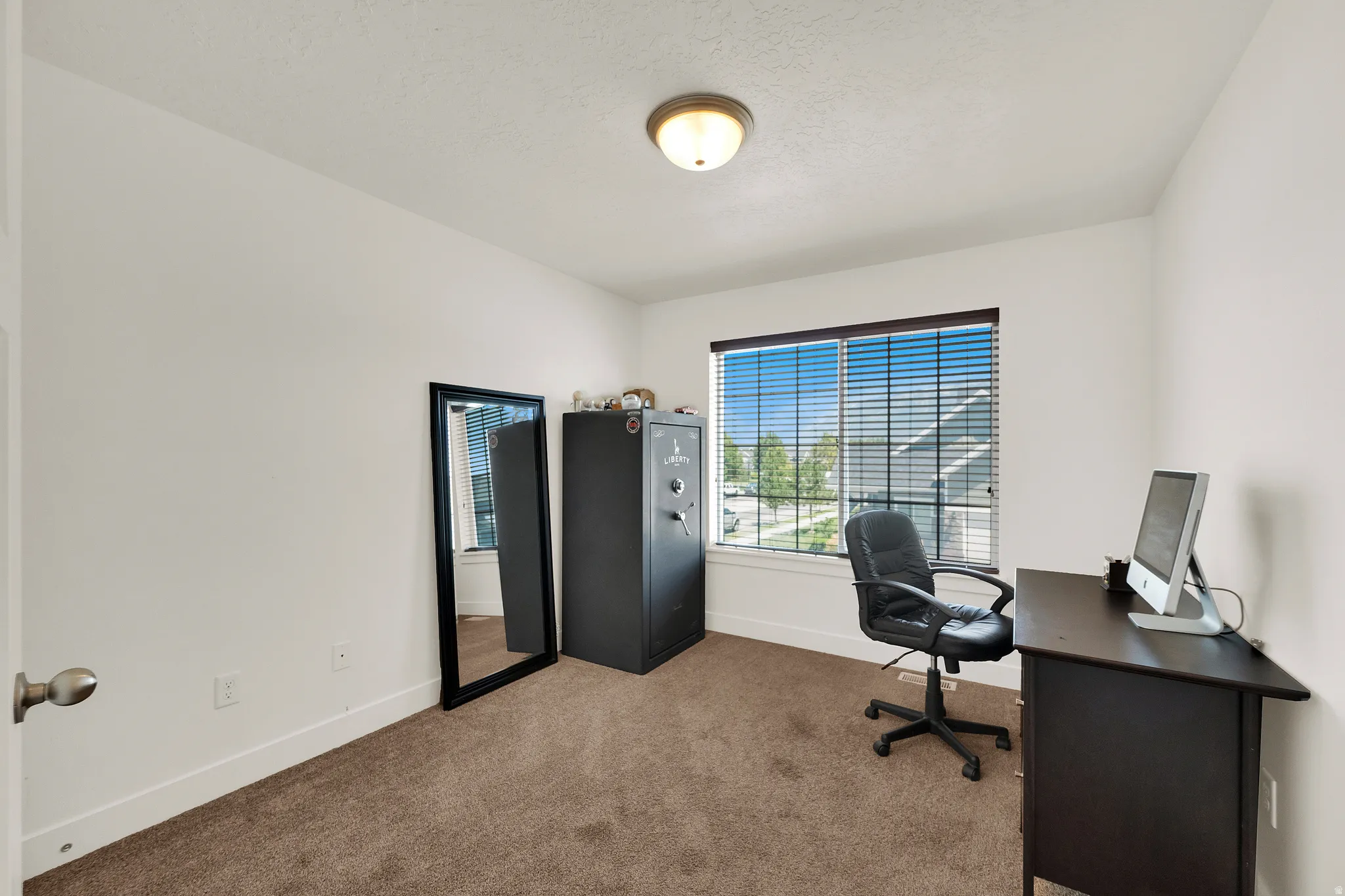 Room featuring a window with horizontal blinds, neutral wall paint, white trim, and brown carpet flooring