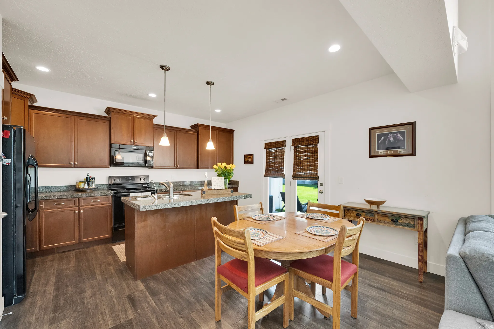 Open-concept kitchen and dining area featuring rich wood-finish cabinetry, speckled countertops, and stainless steel sink