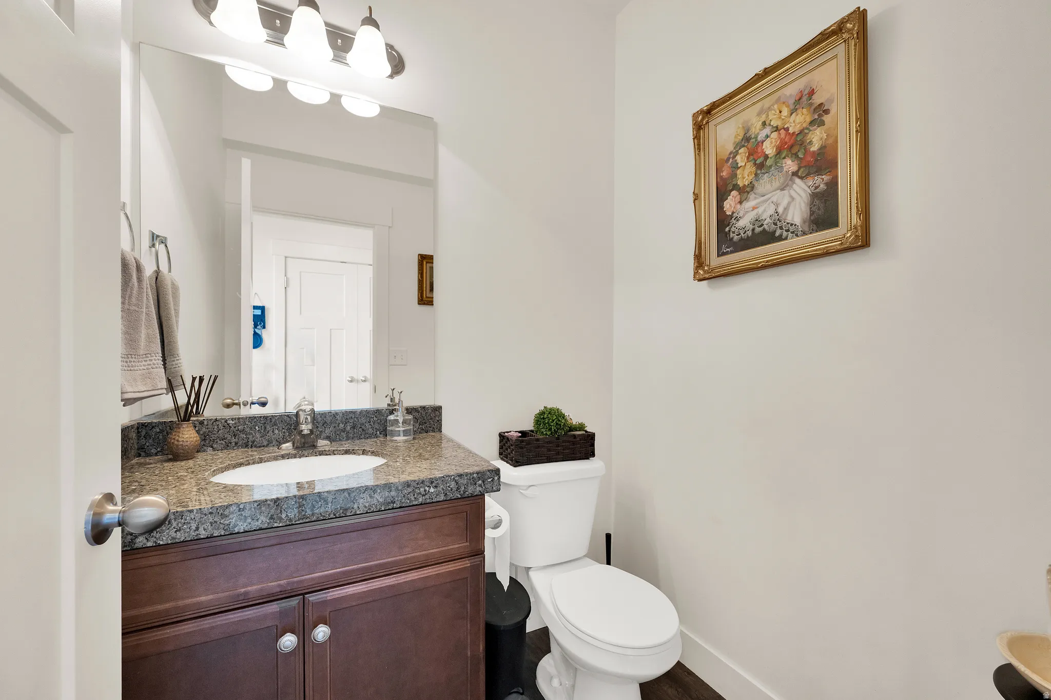 Powder room featuring a dark wood-finish vanity with an undermount sink, granite countertop, and polished chrome faucet