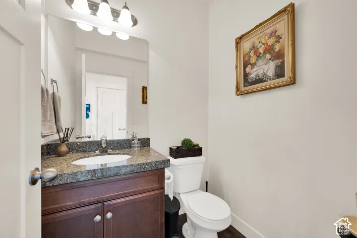 Powder room featuring a dark wood-finish vanity with an undermount sink, granite countertop, and polished chrome faucet