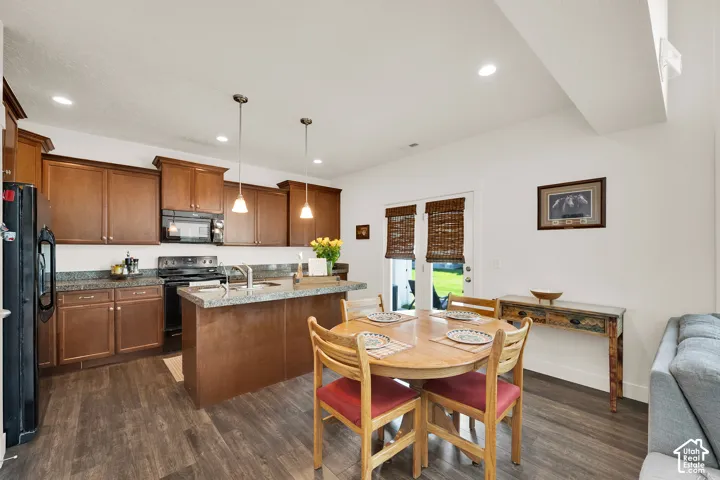 Open-concept kitchen and dining area featuring rich wood-finish cabinetry, speckled countertops, and stainless steel sink