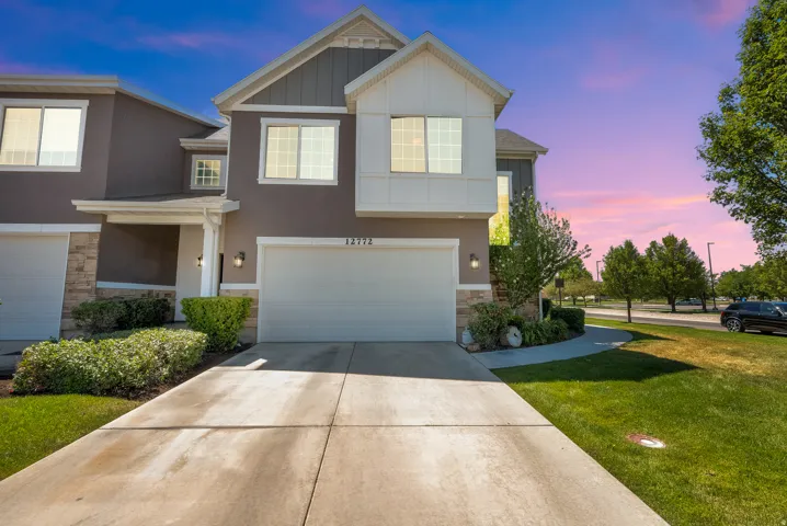 Contemporary townhouse exterior featuring a two-car garage, stone accents, and a covered entry