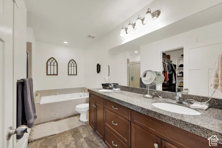 Dual vanity with granite-style countertop, wood-finish cabinetry, and undermount sinks