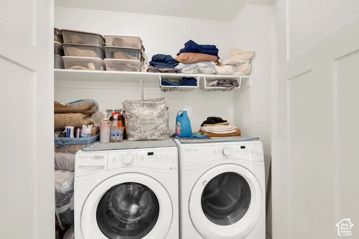 Dedicated laundry alcove featuring white bi-fold doors, two white front-loading washing machines, and integrated shelving for storage