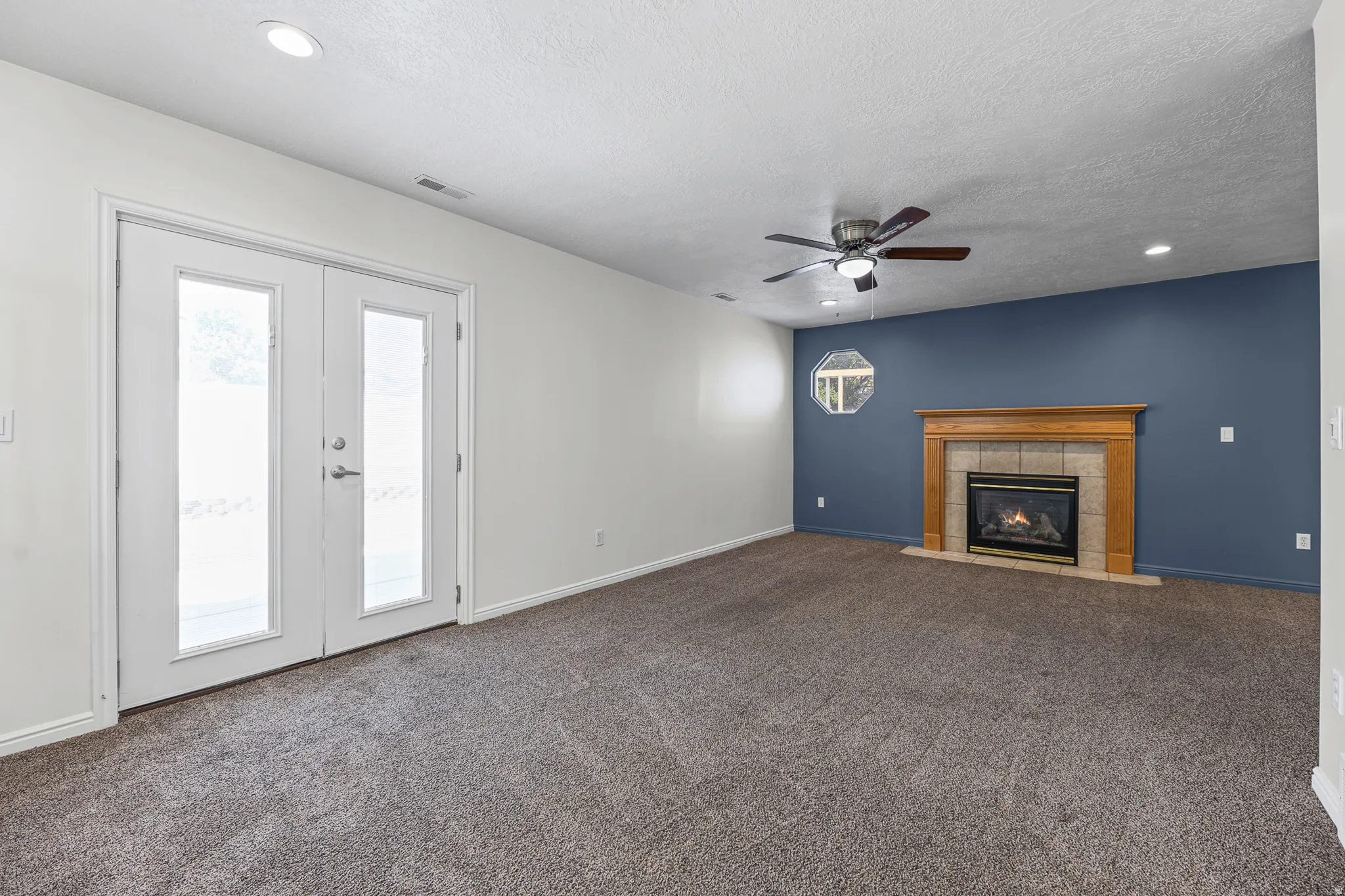 Living area featuring a gas fireplace with a wood mantel and tile surround, recessed lighting, and a ceiling fan