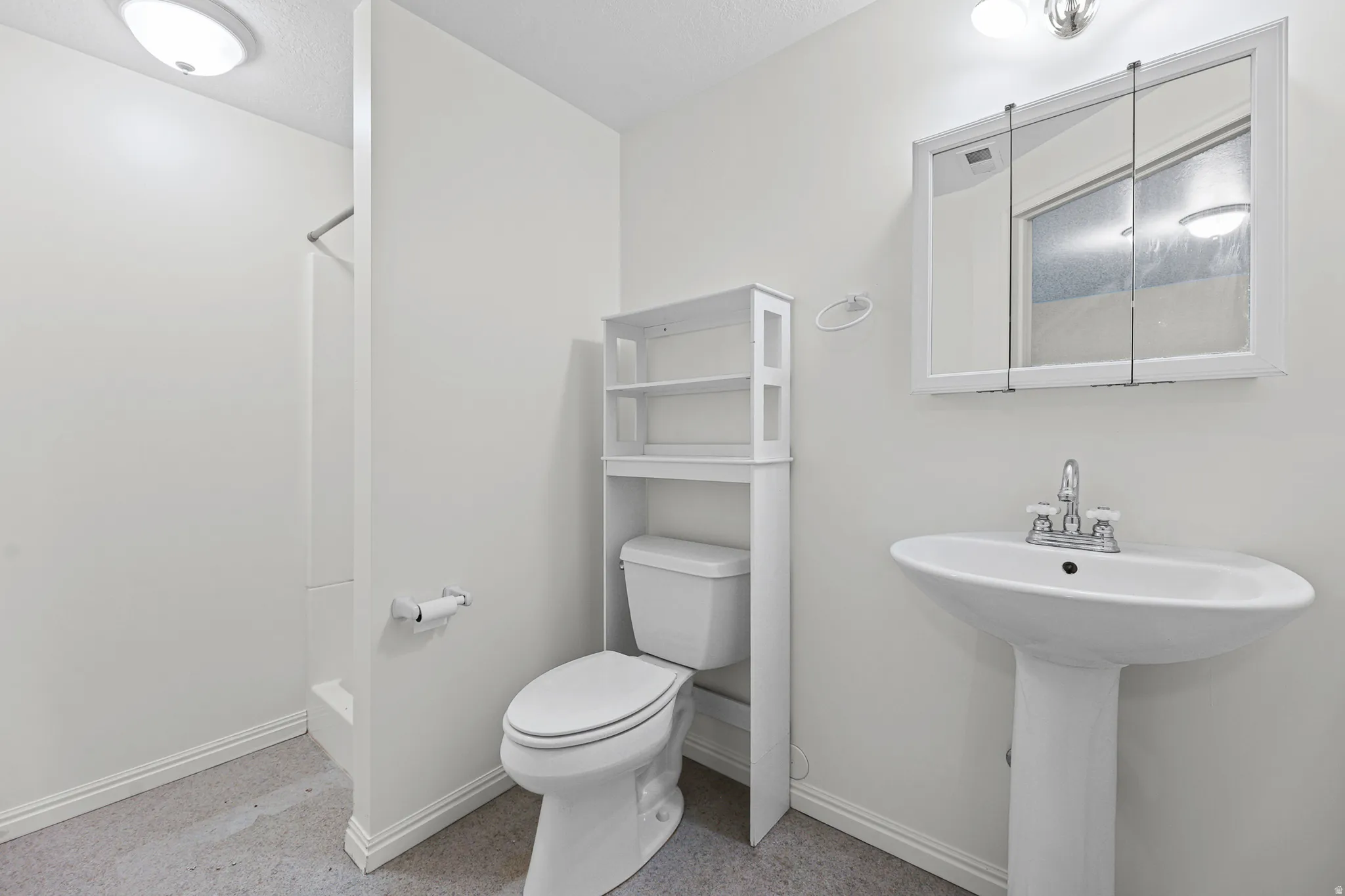 Pedestal sink with chrome faucet and medicine cabinet with mirrored doors