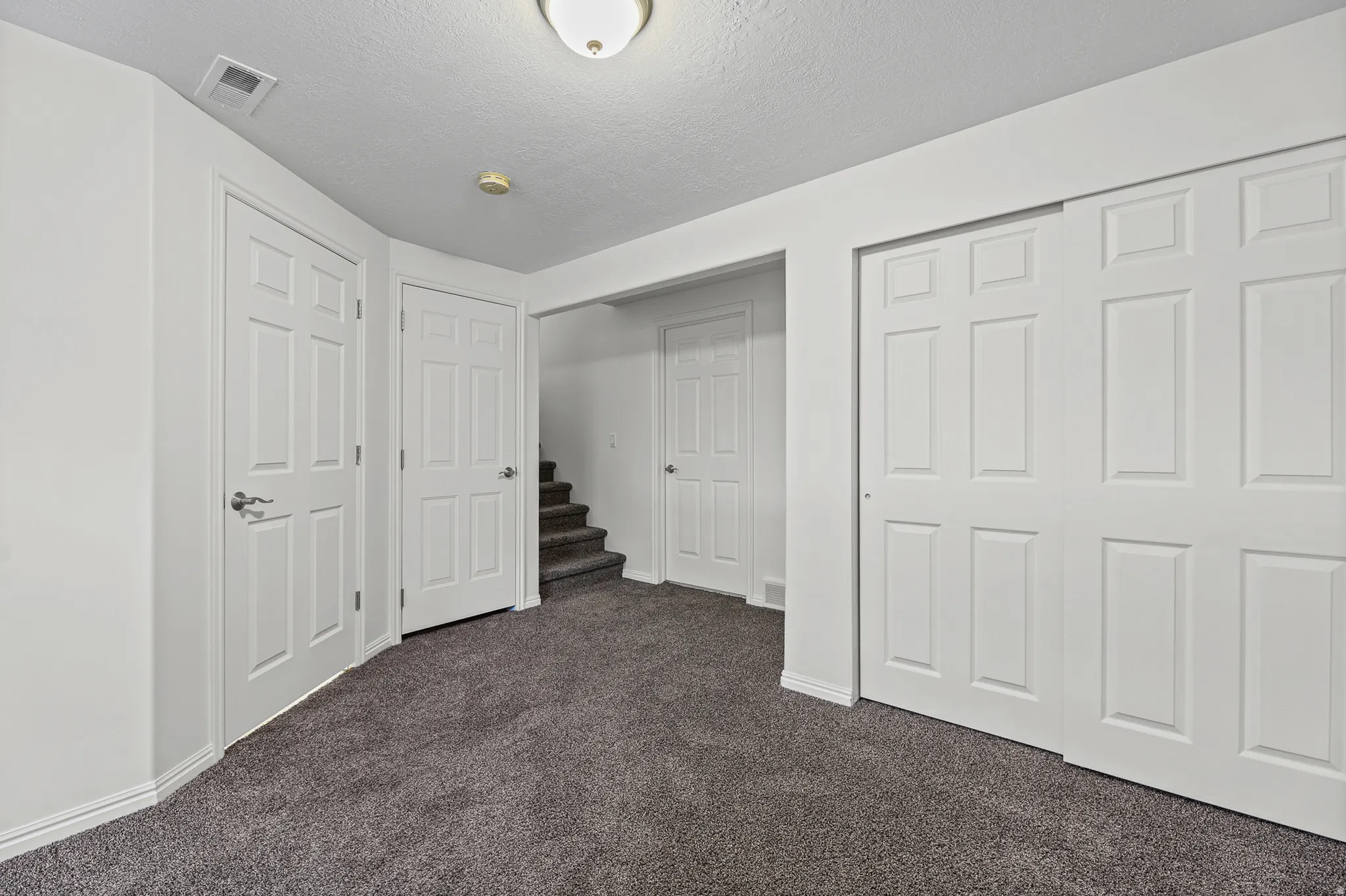 Carpeted room featuring multiple panel doors, white baseboards, and a recessed ceiling light