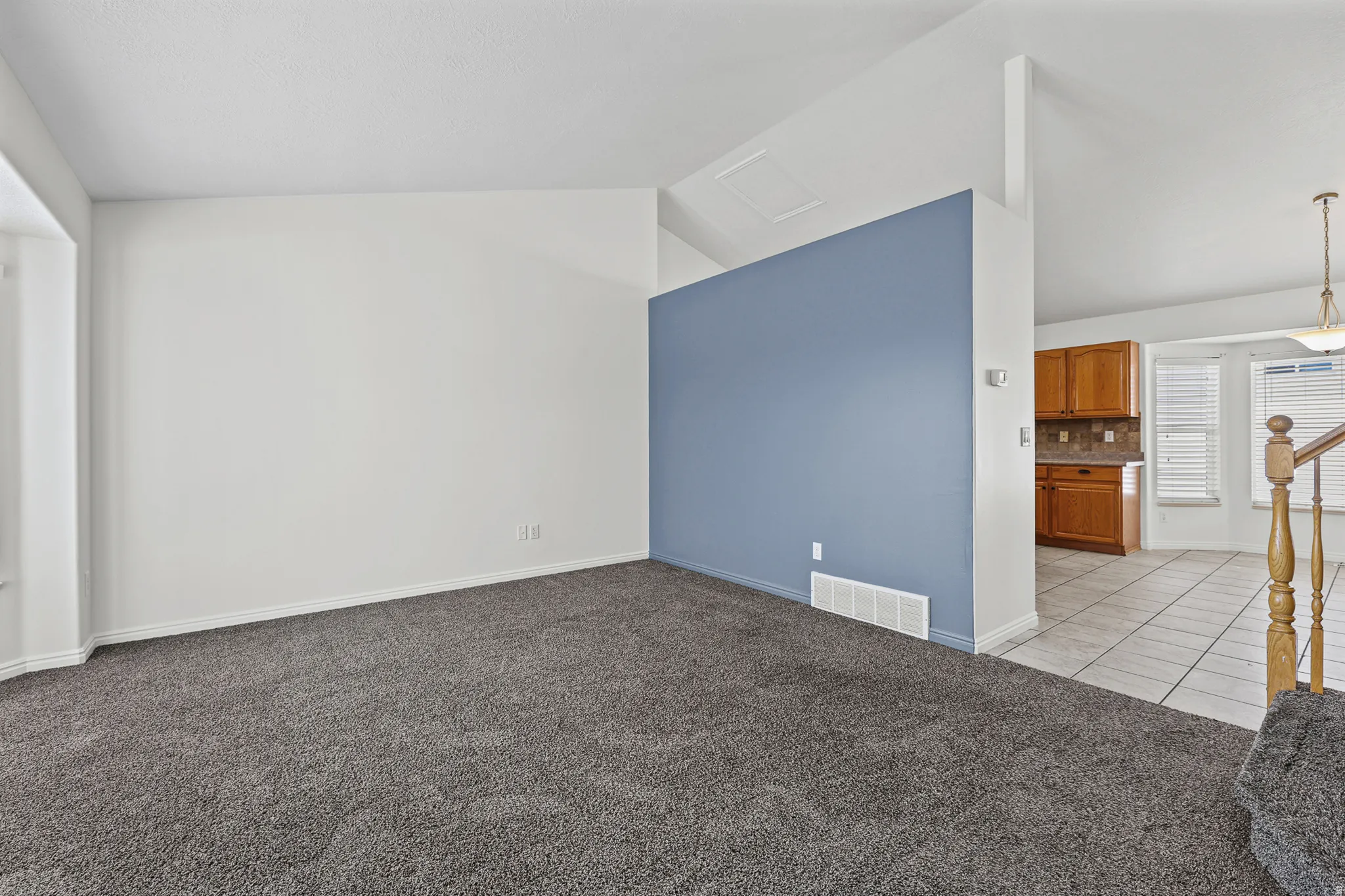 Spacious interior featuring a vaulted ceiling and a partial wall with an accent color