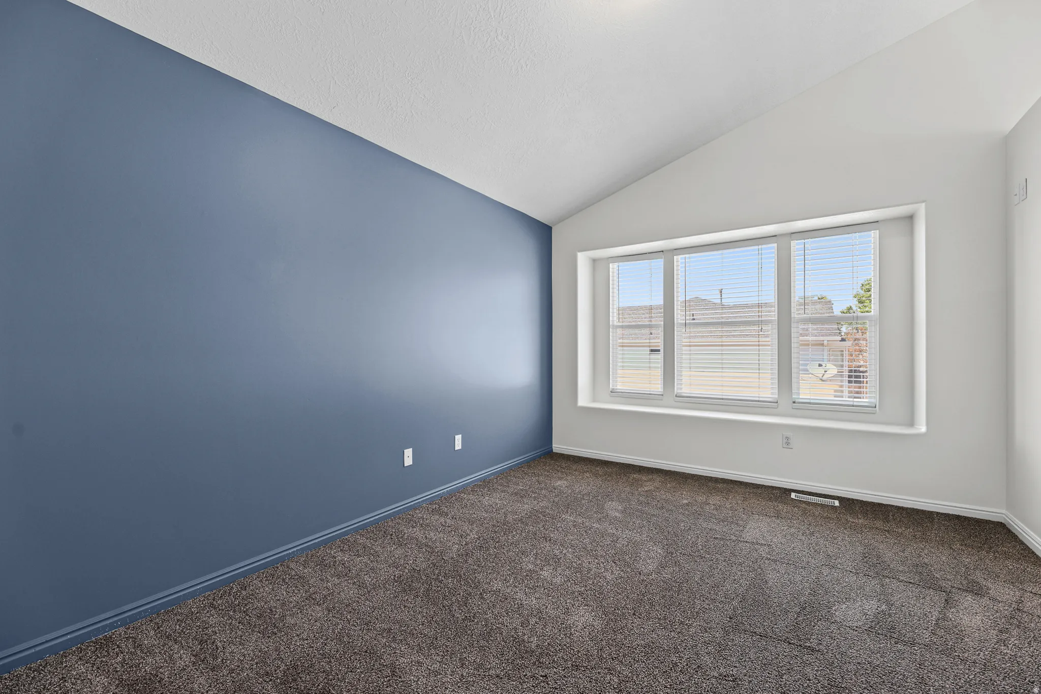 Vaulted ceiling accentuates a multi-panel window with horizontal blinds