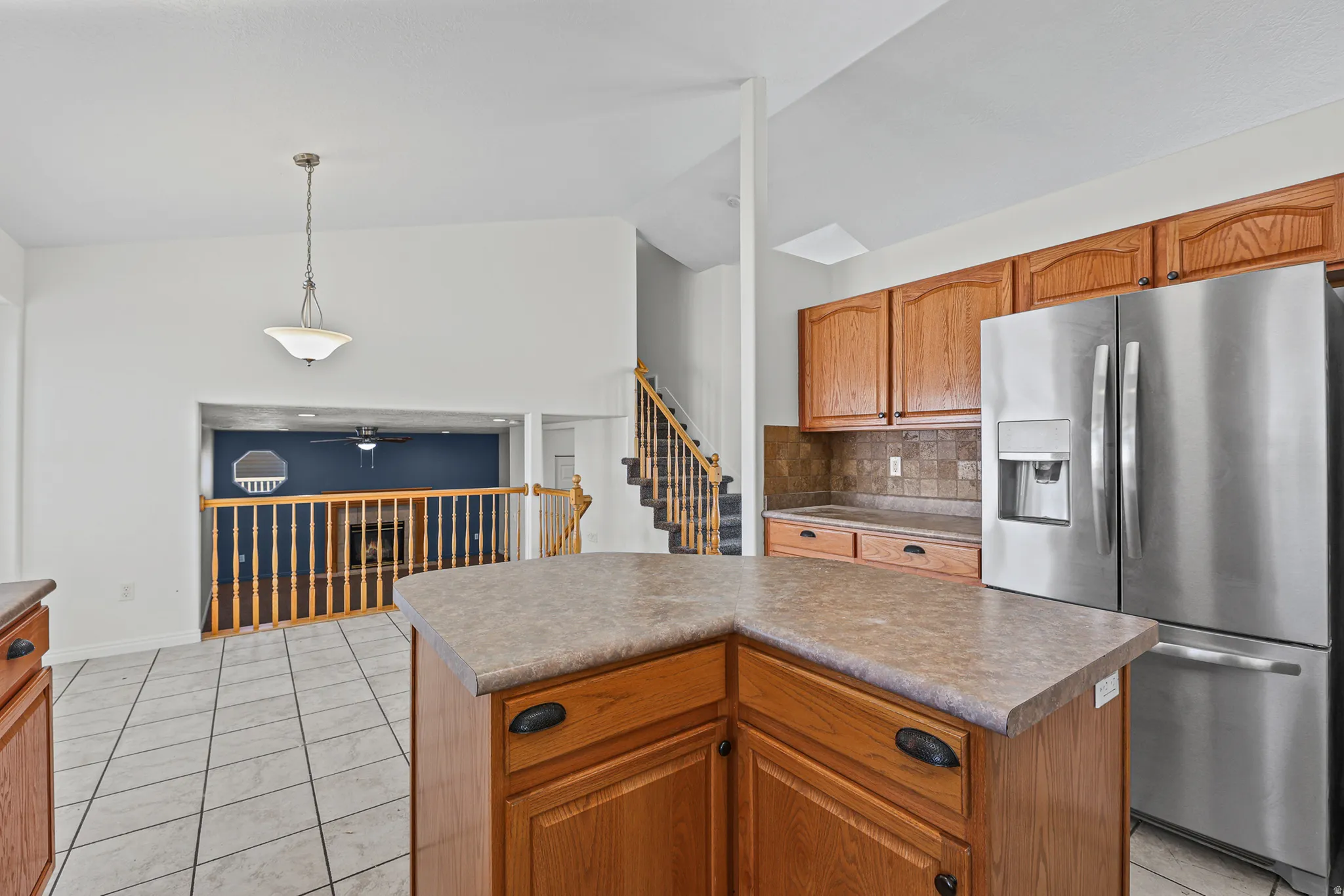 Kitchen featuring an angular island with a laminate countertop, wood cabinetry, and a tile backsplash