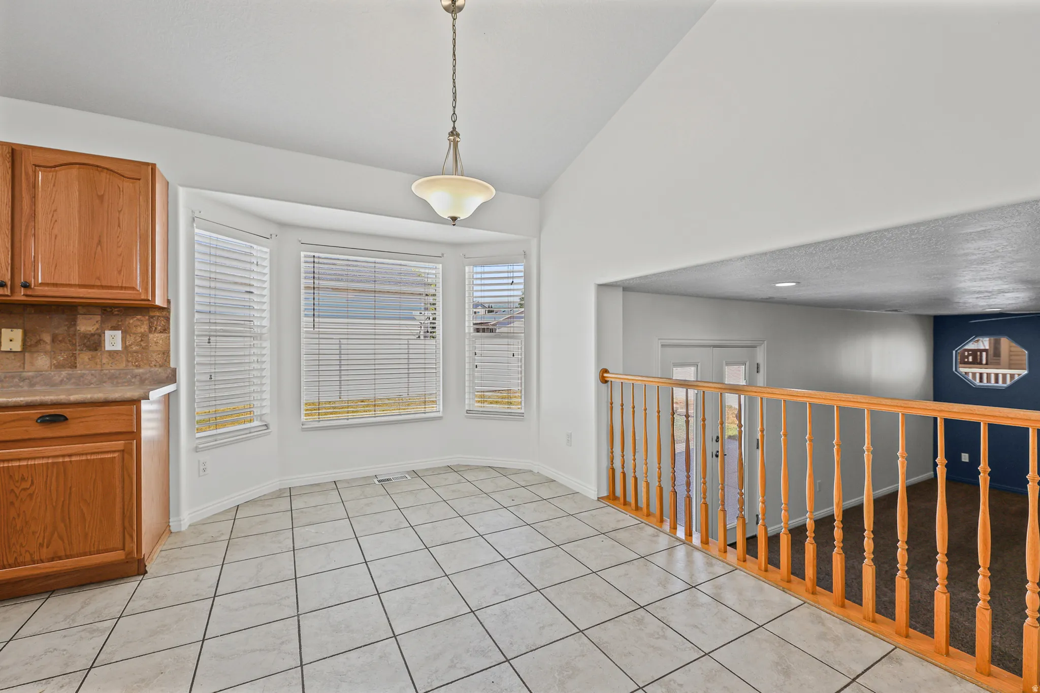 Kitchen dining area featuring a bay window, ceramic tile flooring, oak cabinetry, and a tile backsplash